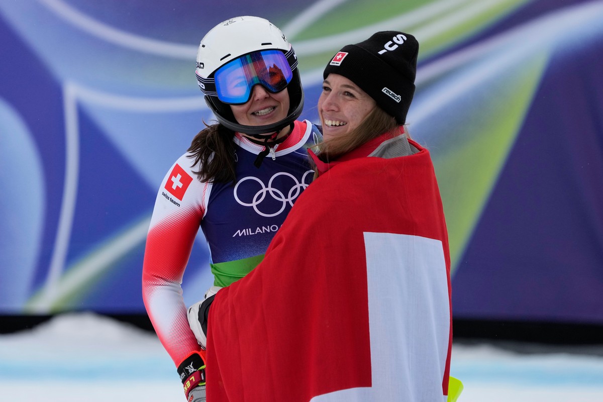 Switzerland's Wendy Holdener, left, is hugged by her teammate Switzerland's Jasmine Flury at the finish area of an alpine ski, women's team combined race, at the 2026 Winter Olympics, i ...